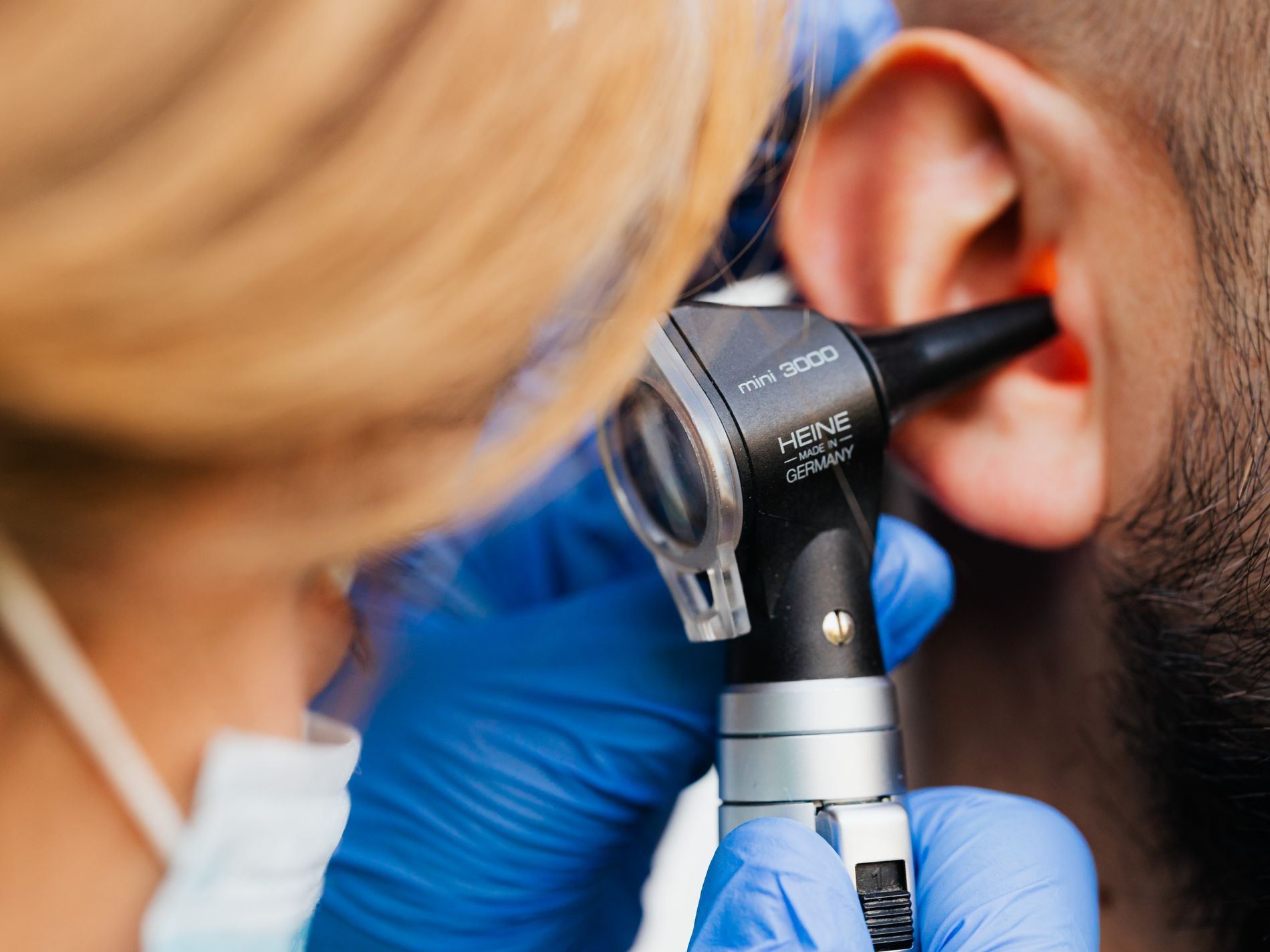 Close-up of a Heine otoscope being inserted into a patient's ear canal